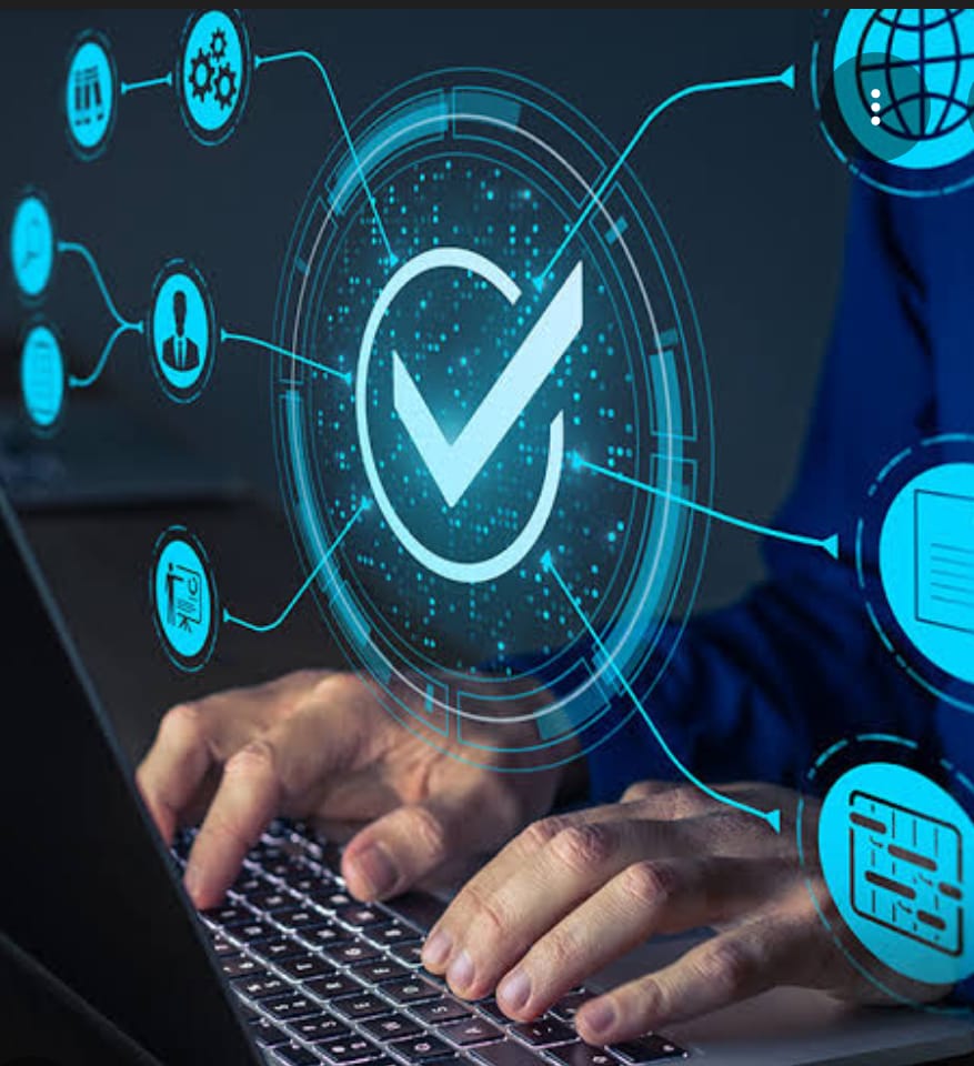 The image shows a person typing on a laptop keyboard with various digital icons and a large checkmark overlaying the scene.
- The person is wearing a blue shirt and typing on a laptop.
- A big glowing blue checkmark is in a circle at the center.
- There are several smaller blue icons around the checkmark connected by lines, including:
- A globe
- A document
- A person icon
- A gear/settings icon
- A chart icon