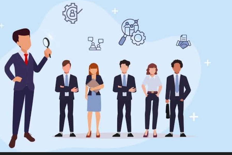 The image shows a cartoon illustration of six business professionals standing in a line, with one person standing separately on the left holding a magnifying glass.

- The person on the left is a man in a dark blue suit with a red tie and brown shoes. He's holding a magnifying glass in his right hand.
- The five people in the line are wearing business attire - suits, ties, and formal shoes. There's a mix of men and women.
- Above them are icons like a gear with a tick, people chatting, a magnifying glass with gears, and a handshake with documents.
- The background is light blue with white plus signs in the corners.