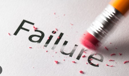 The image shows the word "Failure" written in black text on a white piece of paper. A pencil eraser is rubbing out the word, with pink eraser shavings scattered around. The eraser is positioned on the right side of the image, partially erasing the letters "ur" in "Failure".