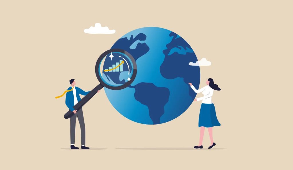 The image shows a cartoon illustration of a man and a woman standing next to a large blue globe.
- The man is on the left, wearing a blue jacket, white shirt, gray pants, and black shoes. He's holding a giant magnifying glass up to the globe.
- Inside the magnifying glass is a bar graph with a yellow line trending upwards.
- The woman is on the right, wearing a white top, blue skirt, and black shoes. She's touching the globe.
- There are two small white clouds above the globe.
- The background of the image is beige.