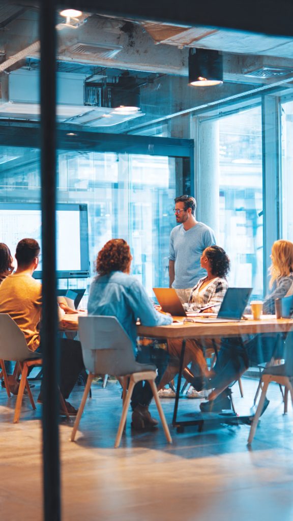 Design Structured Onboarding
A diverse group of professionals participates in a structured onboarding session in a modern office conference room. A team leader stands near a presentation board while new employees sit around a large meeting table, listening attentively. The bright workspace features glass walls, natural lighting, laptops, notebooks, and collaborative discussions, representing employee onboarding, team integration, and workplace training in a fast-growing organization.